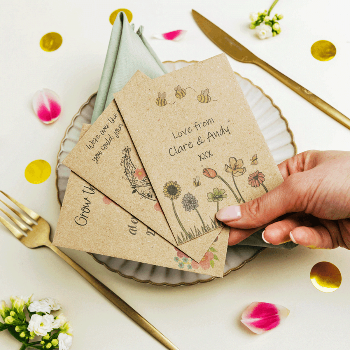 Hand holding personalised wildflower seed paper favours with floral illustrations